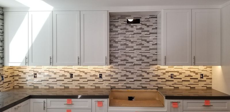 Kitchen with white cabinets, tiled backsplash, and recessed shelving.