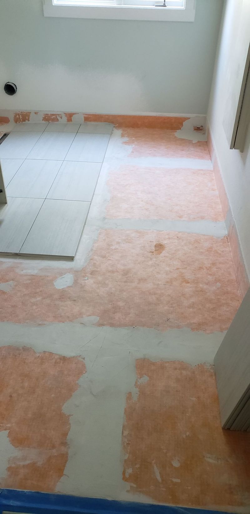 Interior construction showing an orange water membrane applied to the subfloor, with some cement board and a window.