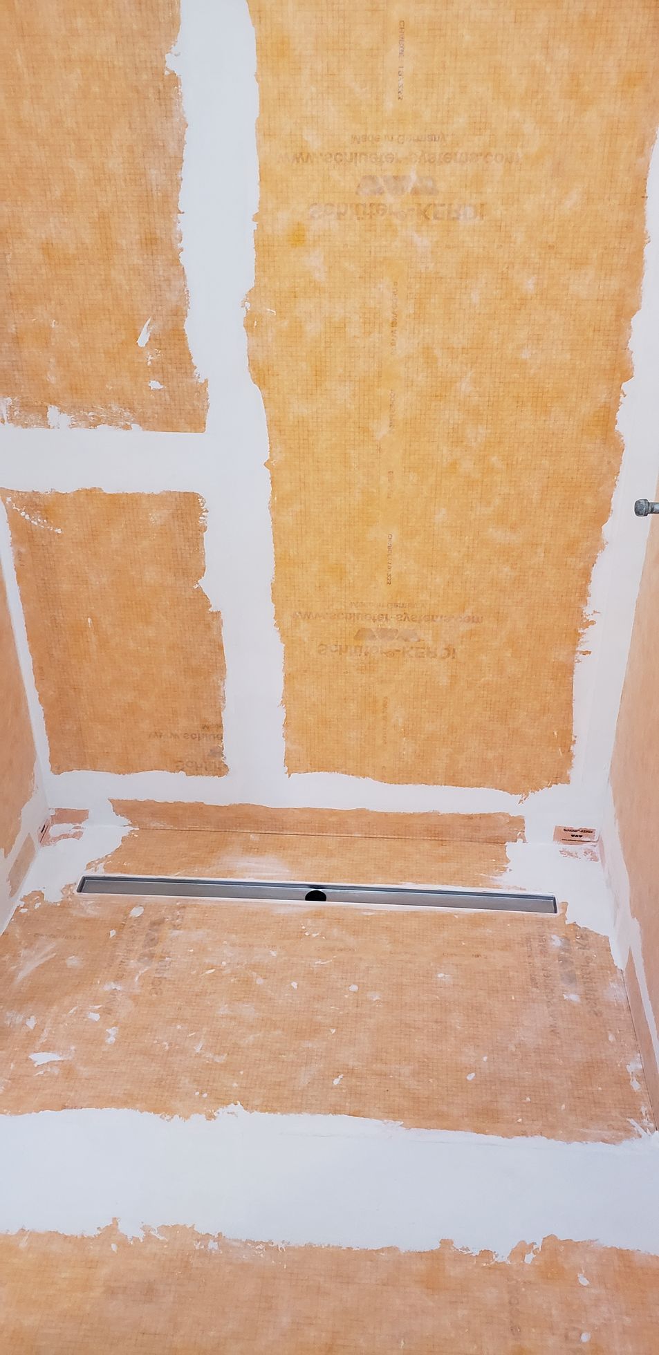 Construction of shower base with a linear drain. Walls are plastered.