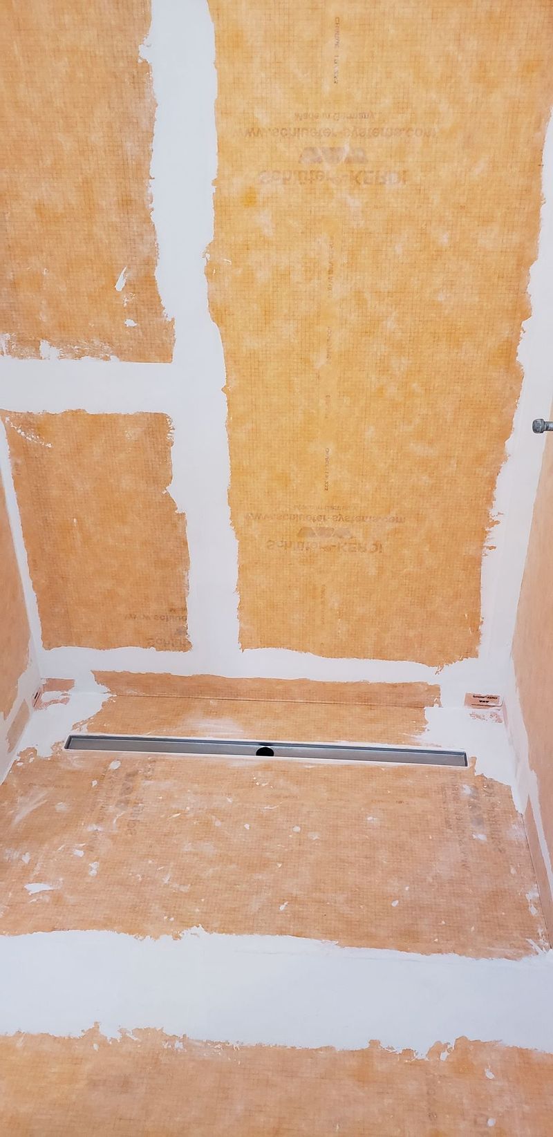 Construction of shower base with a linear drain. Walls are plastered.