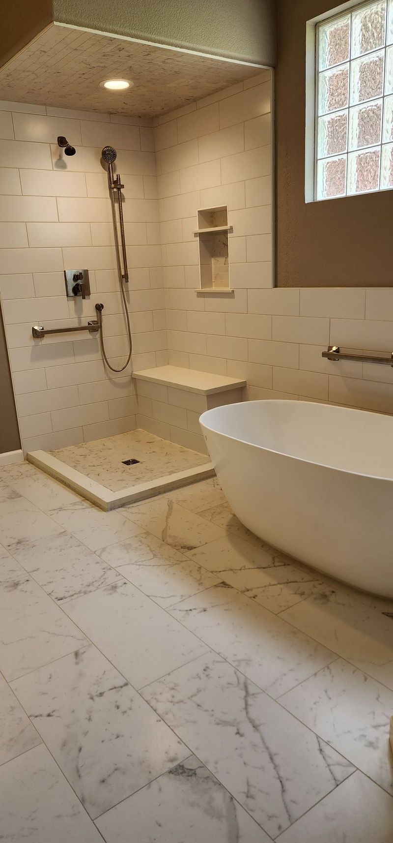 A modern bathroom with a white bathtub, shower, and marble flooring.
