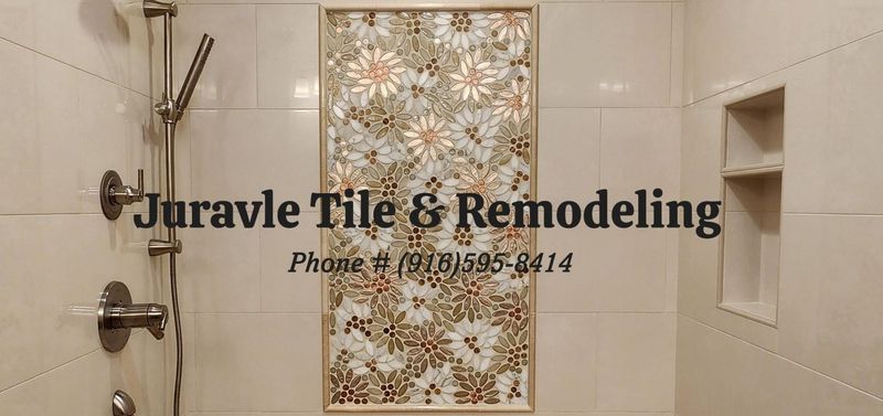 Shower remodel with floral tile insert, shower head, and built-in shelf. Beige and silver tones.