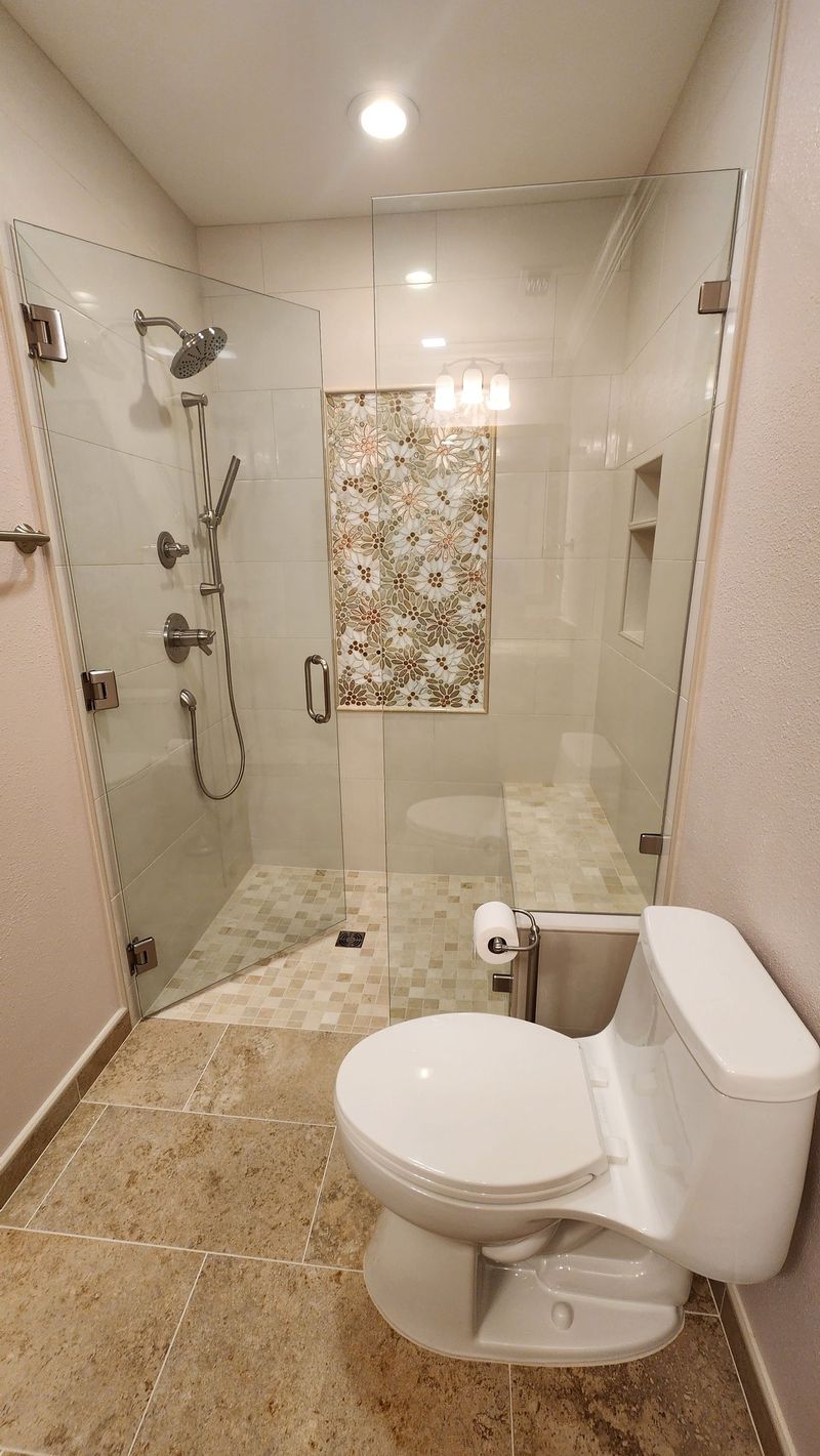 Bathroom with glass-enclosed shower, toilet, and light-colored walls and floor.
