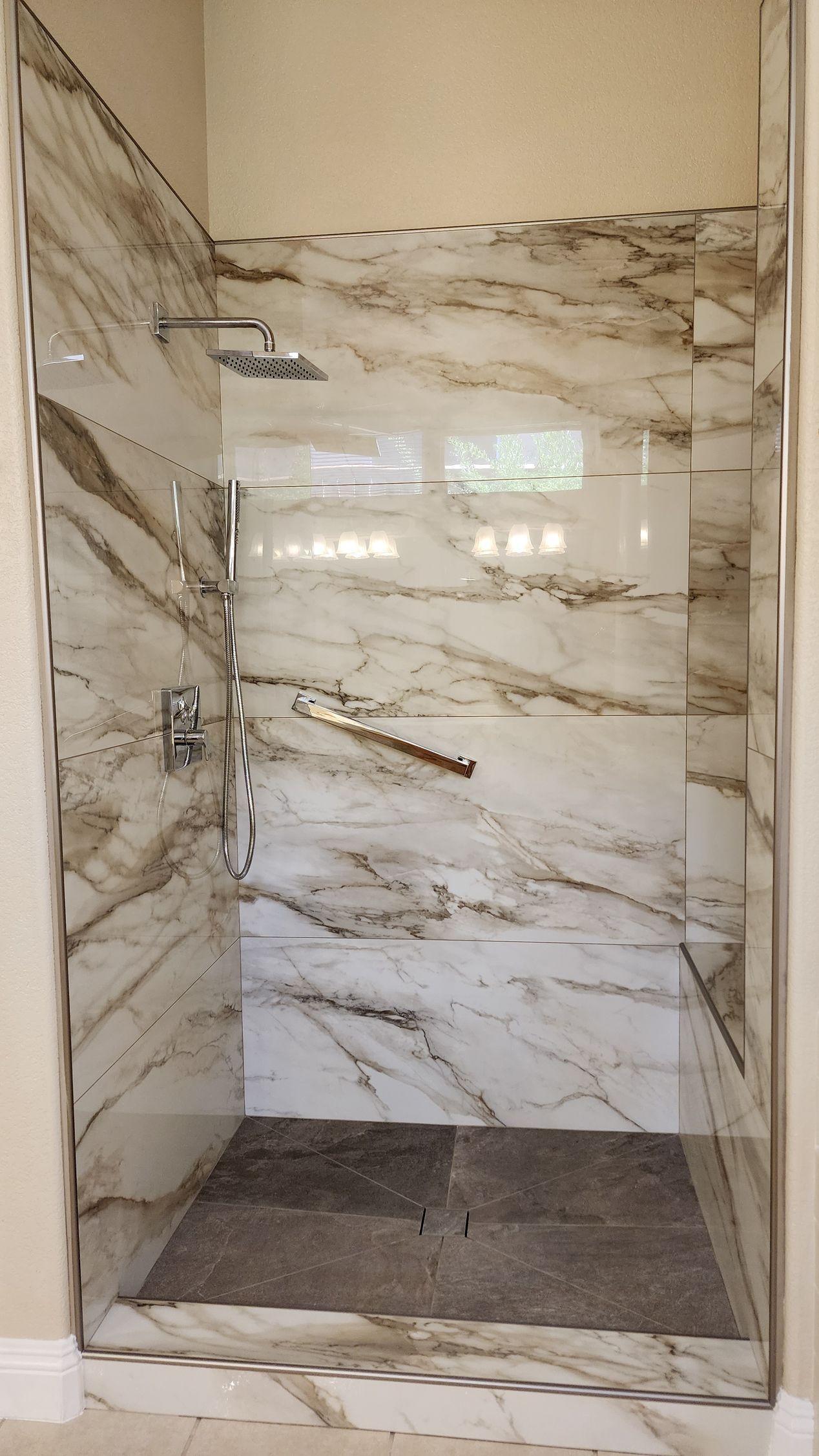Marble-tiled shower with a clear glass door. A showerhead and faucet are visible.