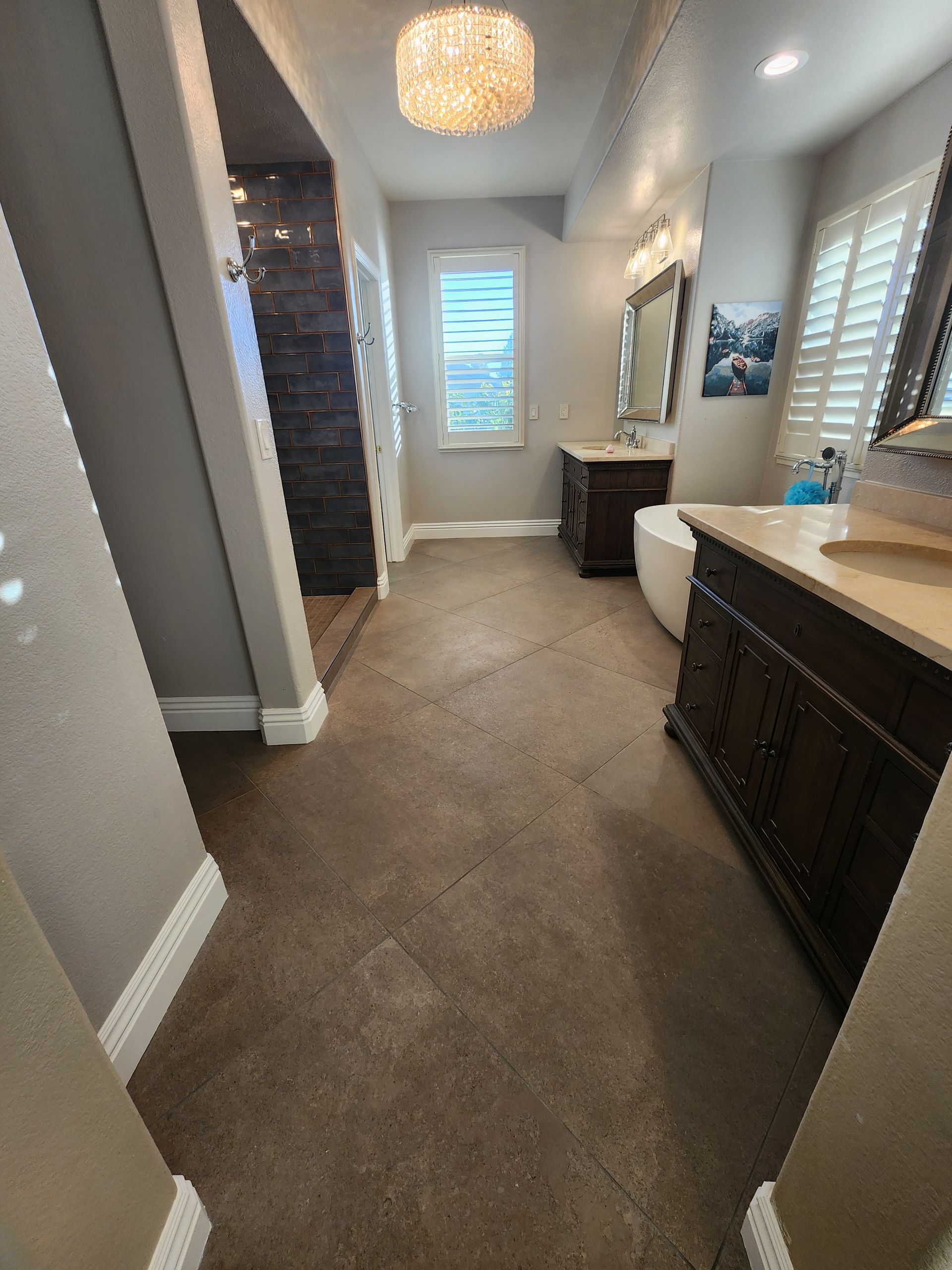 Bathroom with brown floor, dark wood vanity, white tub, and decorative light fixture.
