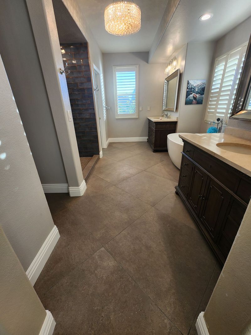 Bathroom with brown floor, dark wood vanity, white tub, and decorative light fixture.