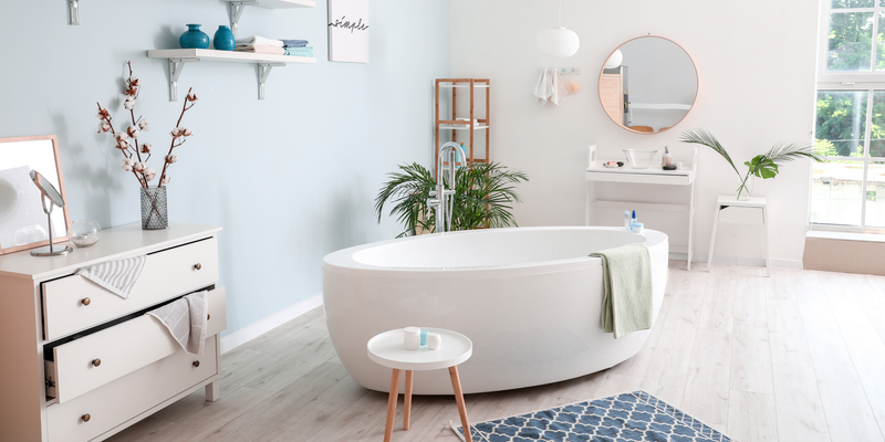 Modern bathroom with a white oval bathtub, plants, and natural light.