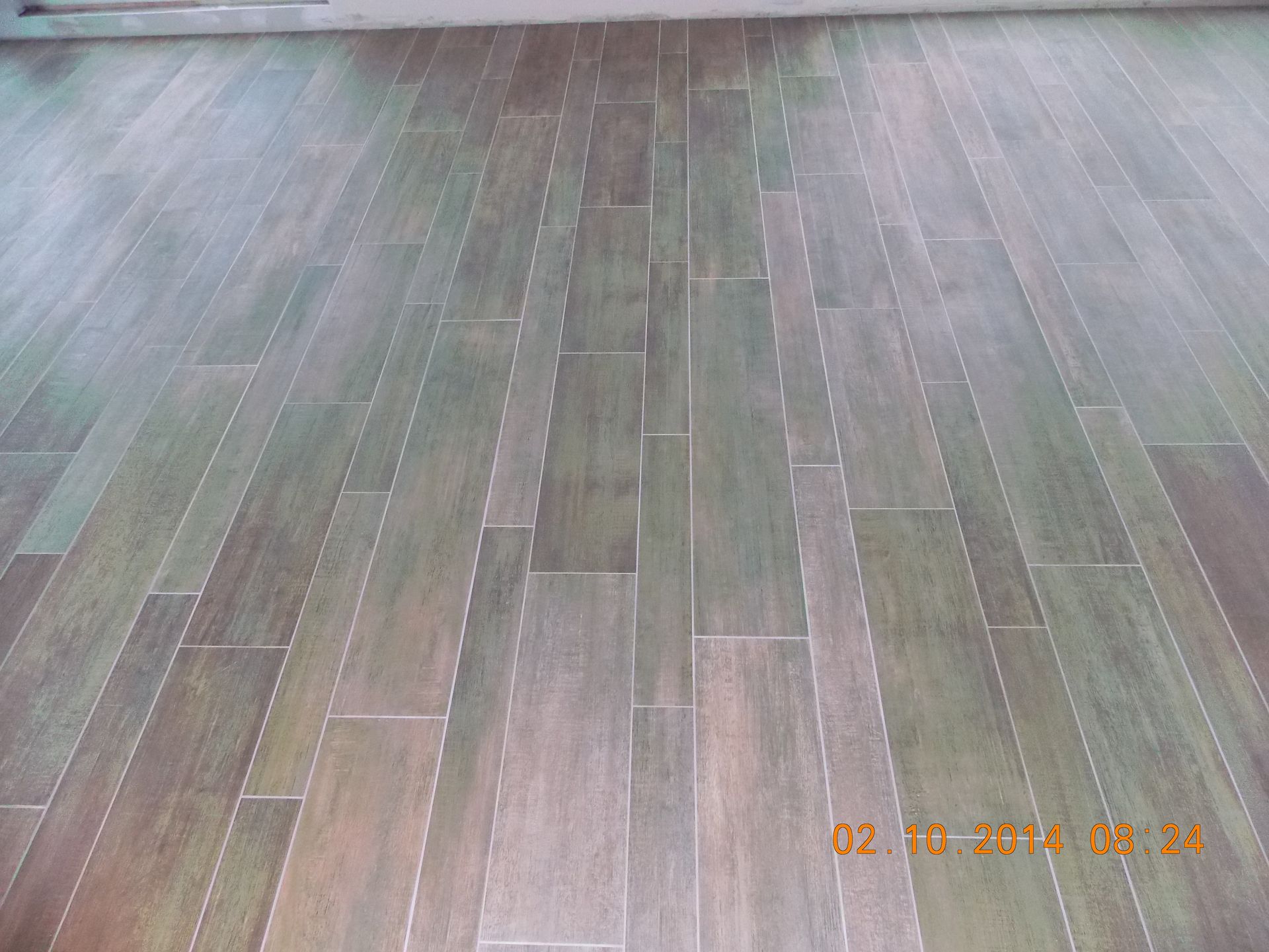 Wood-look tile flooring in shades of gray and brown, installed in a staggered pattern.
