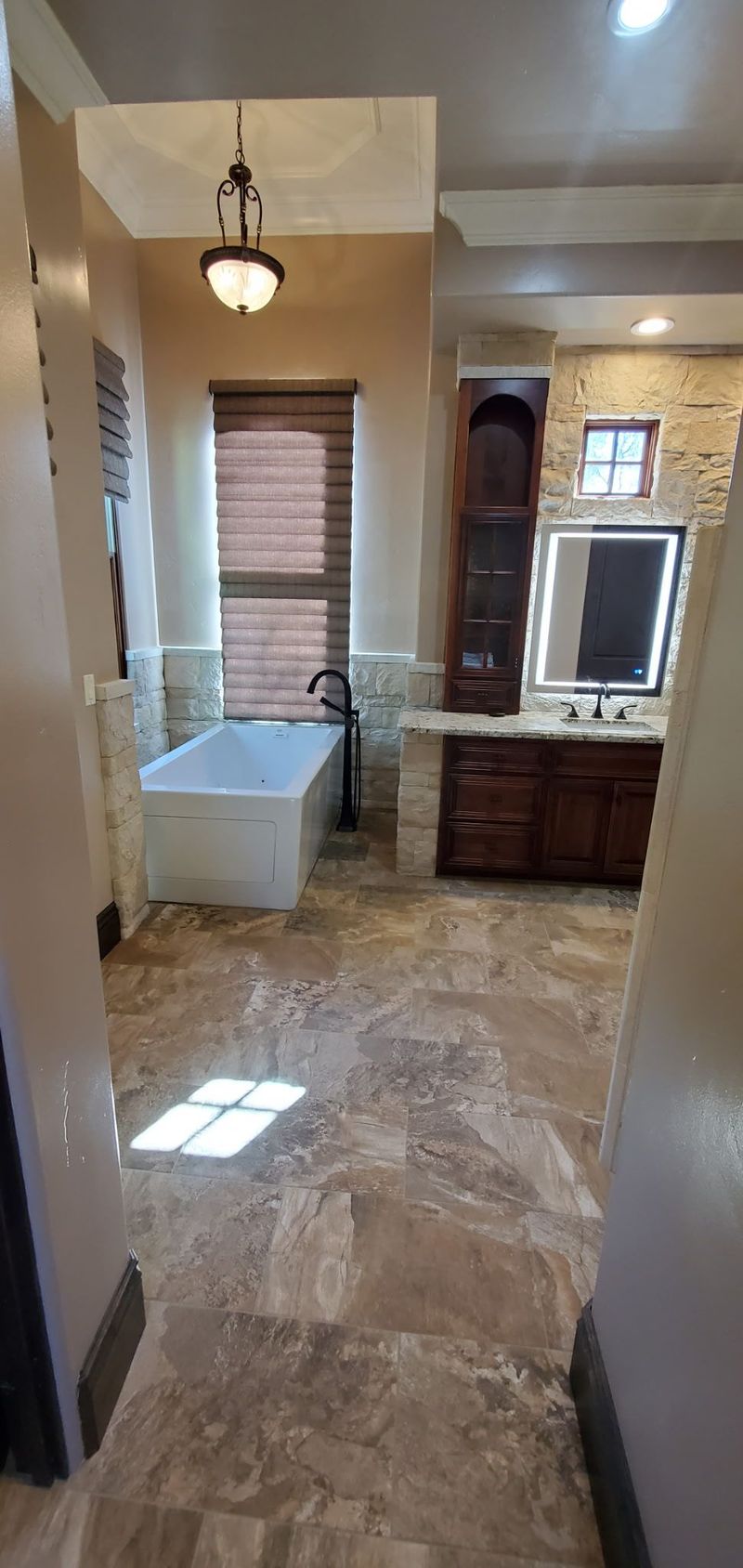 Bathroom with a freestanding tub, dark wood vanity, and a window with blinds.