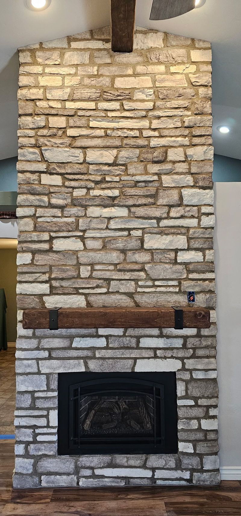 Stone fireplace with wooden mantle and dark firebox.