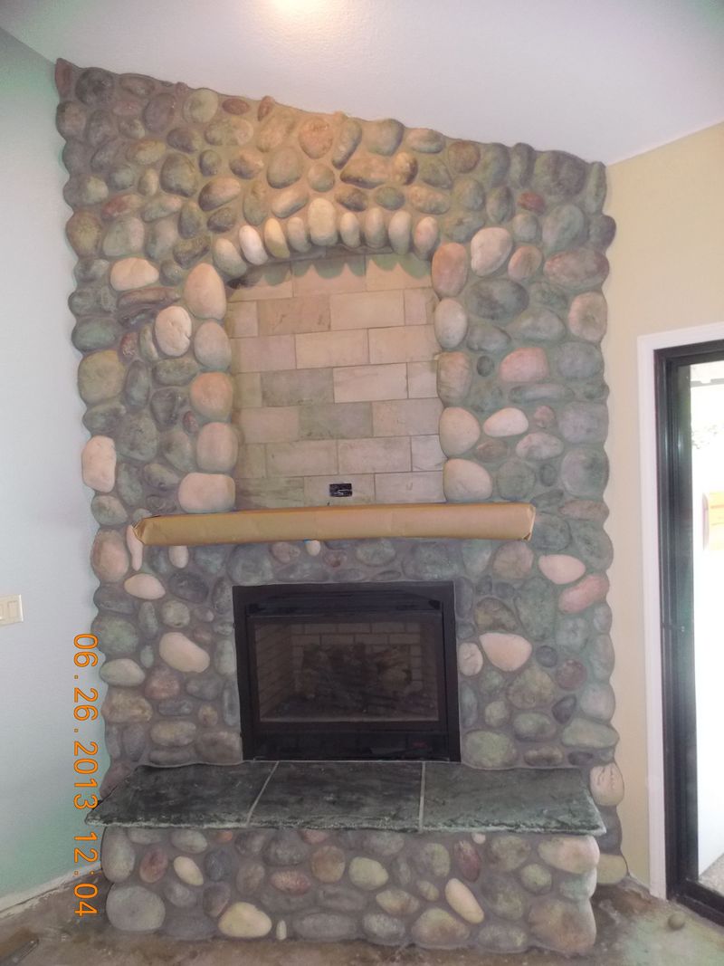 Stone fireplace with a dark framed firebox, topped by a wooden mantle.