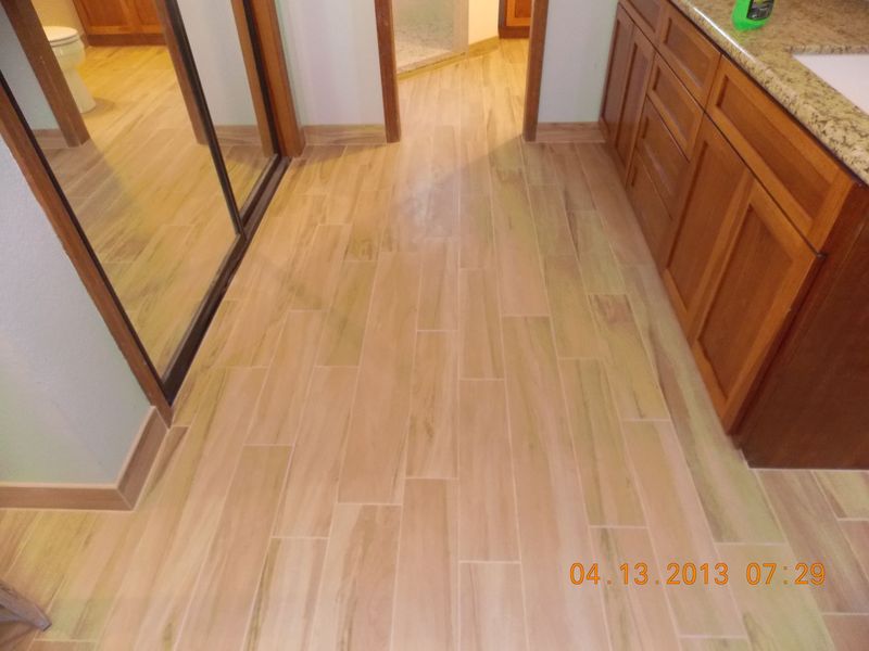 Bathroom with light wood-look floor tiles, dark wood cabinets, and a mirror.
