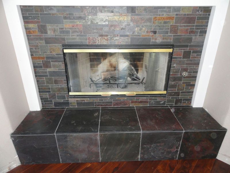 Fireplace with dark stone surround and hearth, with a glass door and white trim.
