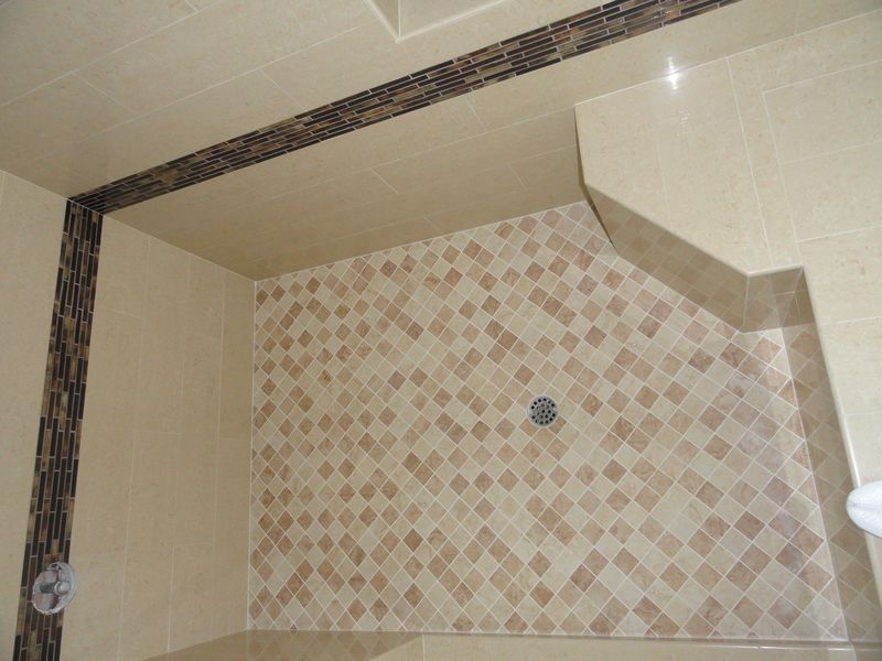 Beige and brown tiled shower with mosaic border.