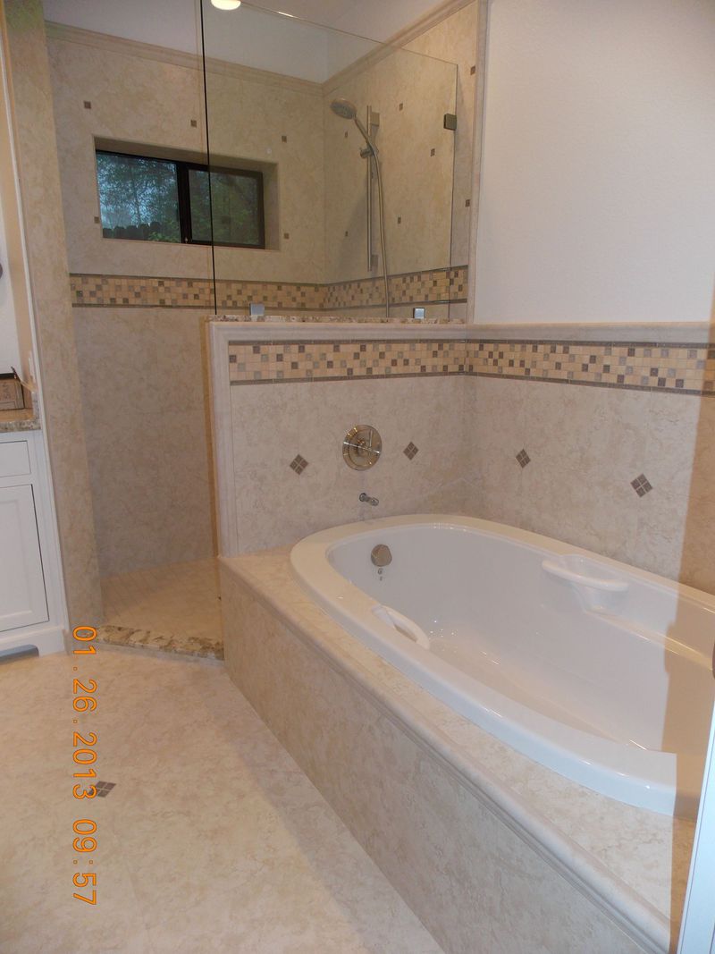 Bathroom with a white bathtub and beige tiled walls and floor.