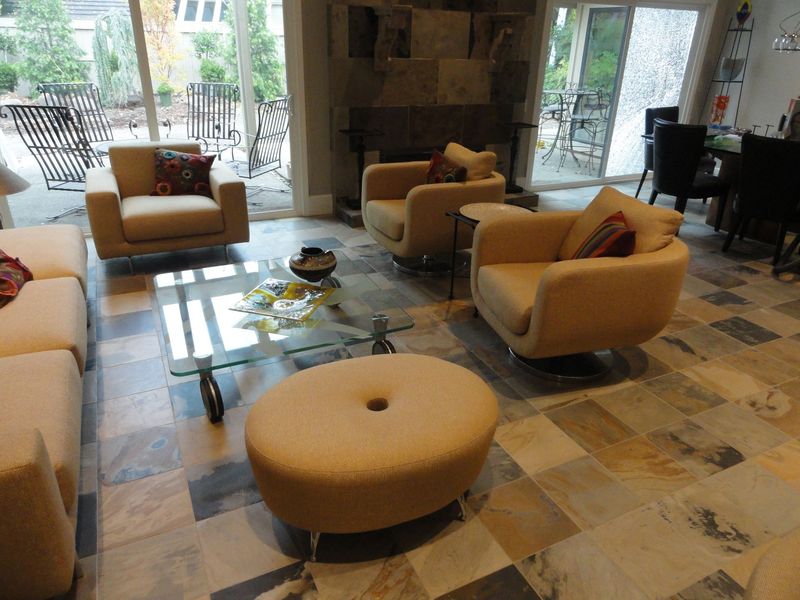 Living room with beige furniture, glass coffee table, stone floor, and a view of the outside.