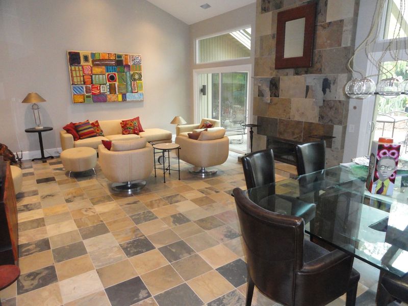 Living room with stone fireplace, modern furniture, colorful art, and checkered tile floor.