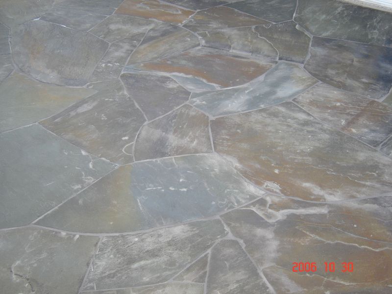 Stone tile flooring, irregular shapes, muted blues, browns, and grays.