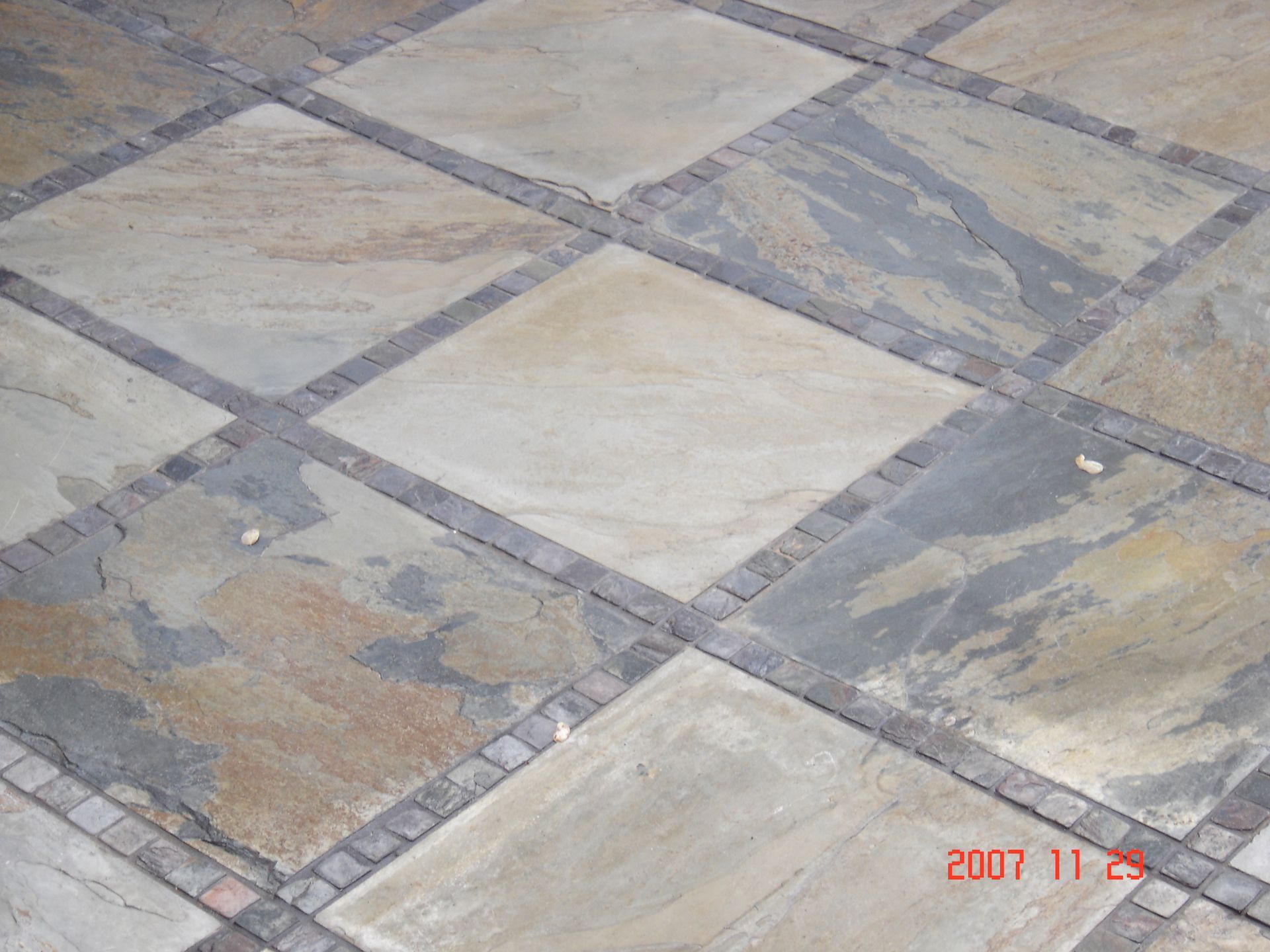 Diamond pattern stone tile flooring with a brick border.