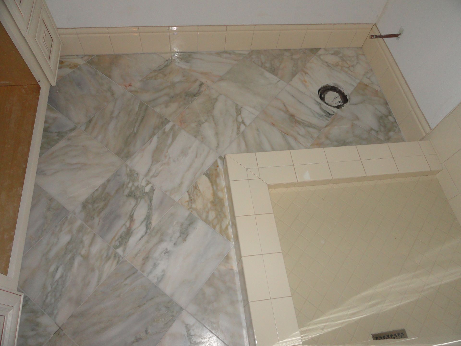 Bathroom with light marble tile floor, beige wall tiles, and shower area.