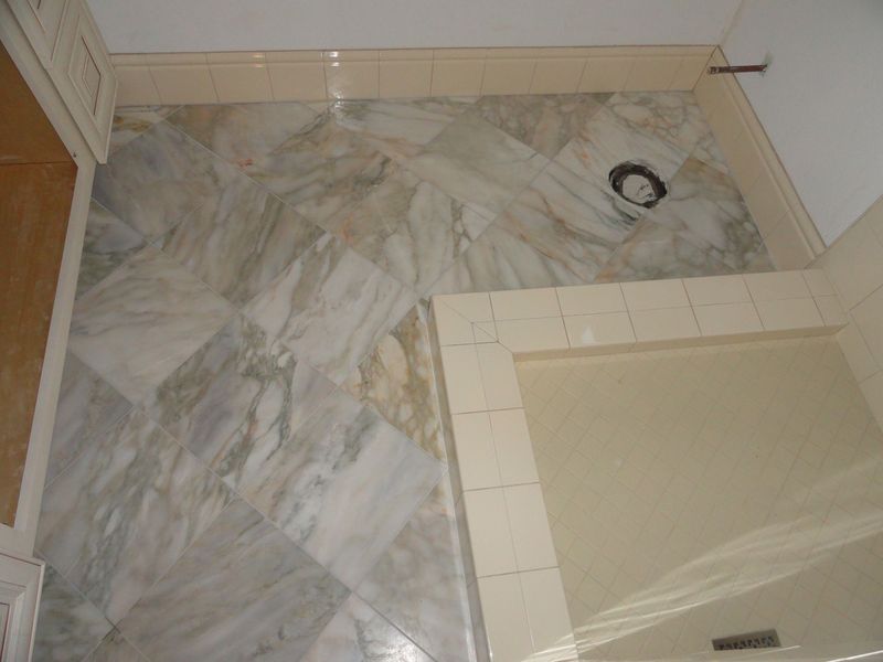 Bathroom with light marble tile floor, beige wall tiles, and shower area.