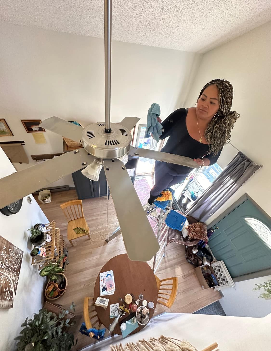 A woman is carrying a mattress in a messy room.
