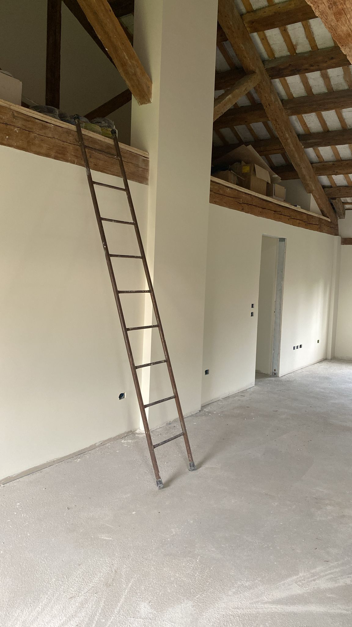 Una stanza vuota con una scala che sale fino al soffitto.