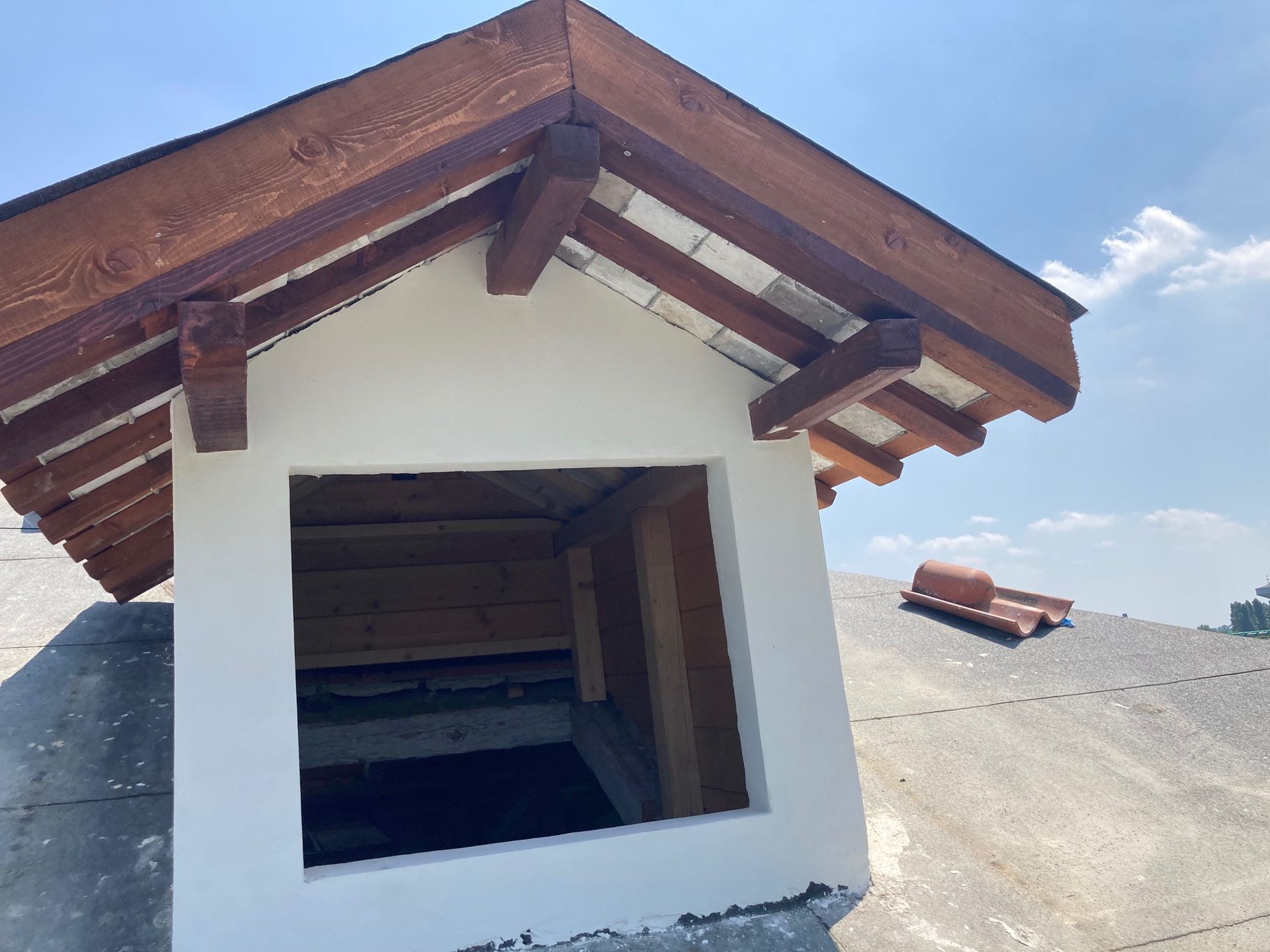 Un piccolo edificio bianco con un tetto di legno e una finestra