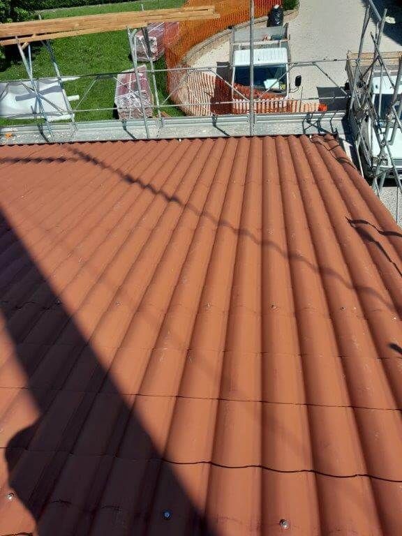 Un tetto di tegole rosse è in costruzione sulla cima di un edificio.