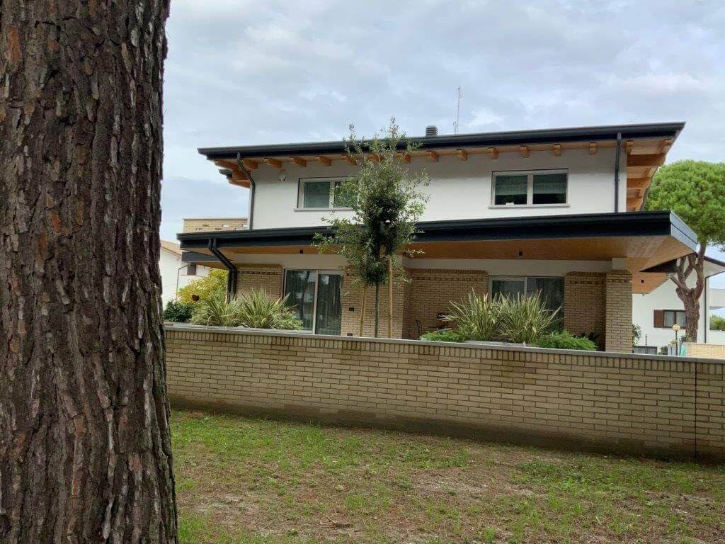Una casa con un muro di mattoni e un albero di fronte