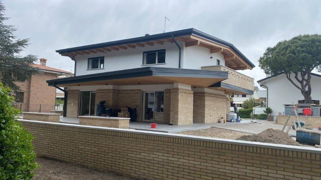 Si sta costruendo una grande casa con un muro di mattoni davanti.