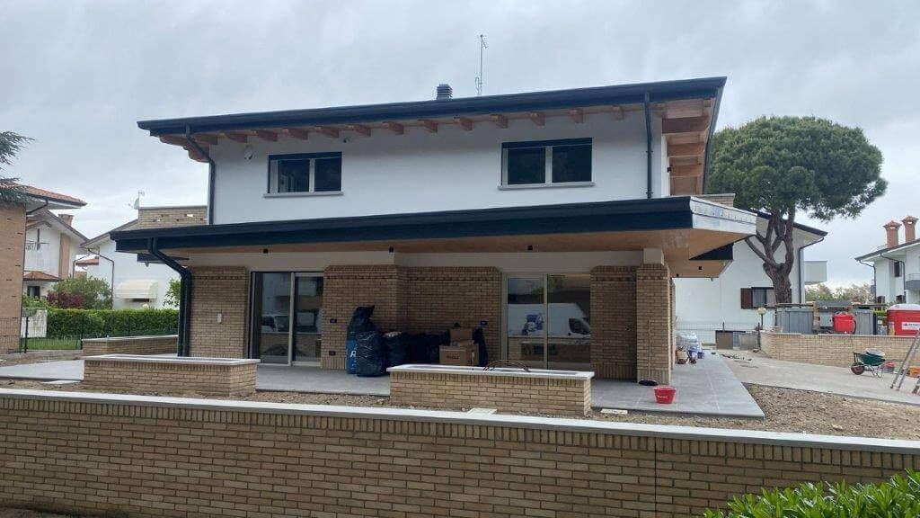 Una grande casa bianca con un muro di mattoni davanti.