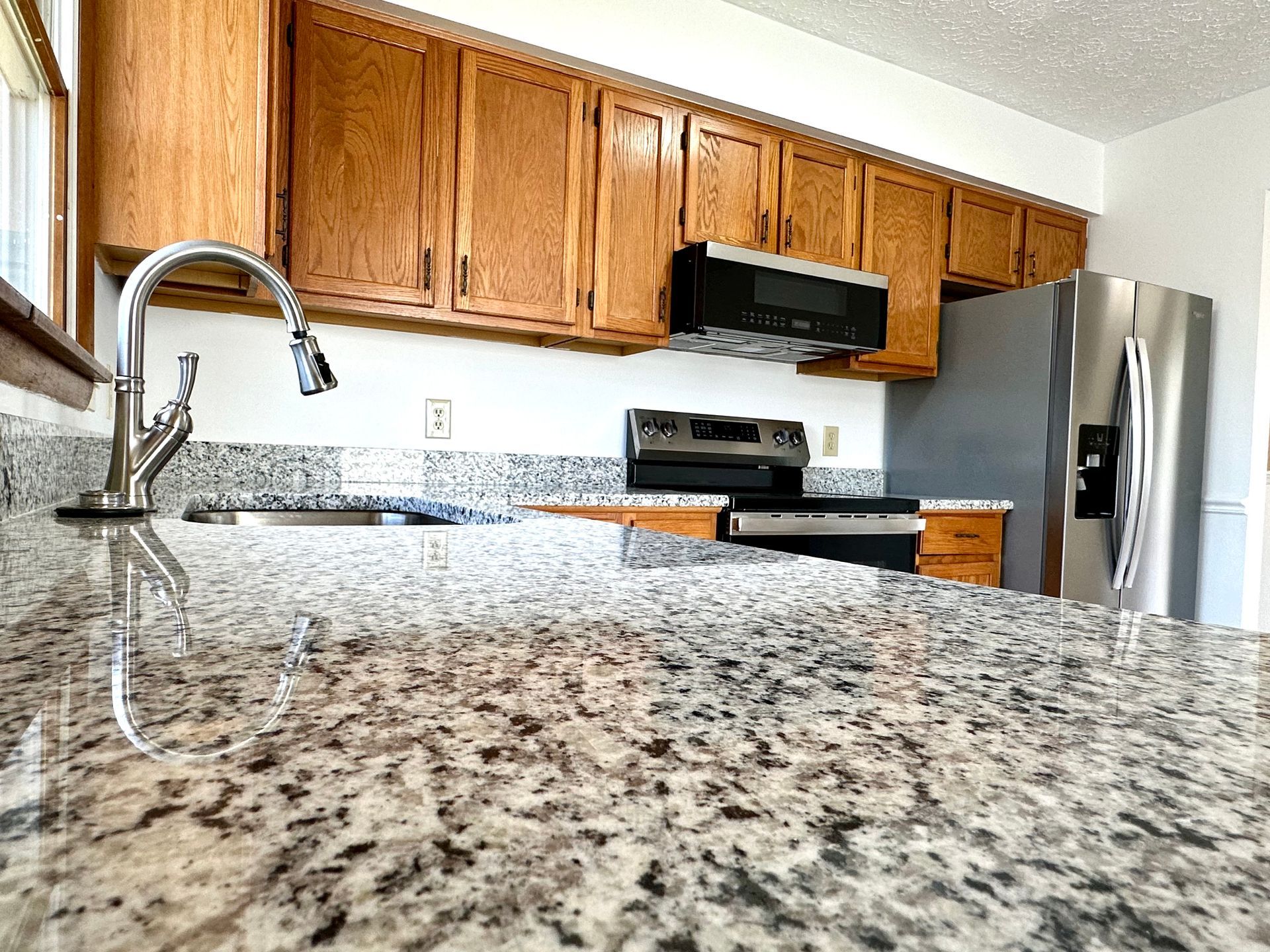 A kitchen with granite counter tops , stainless steel appliances , and wooden cabinets.