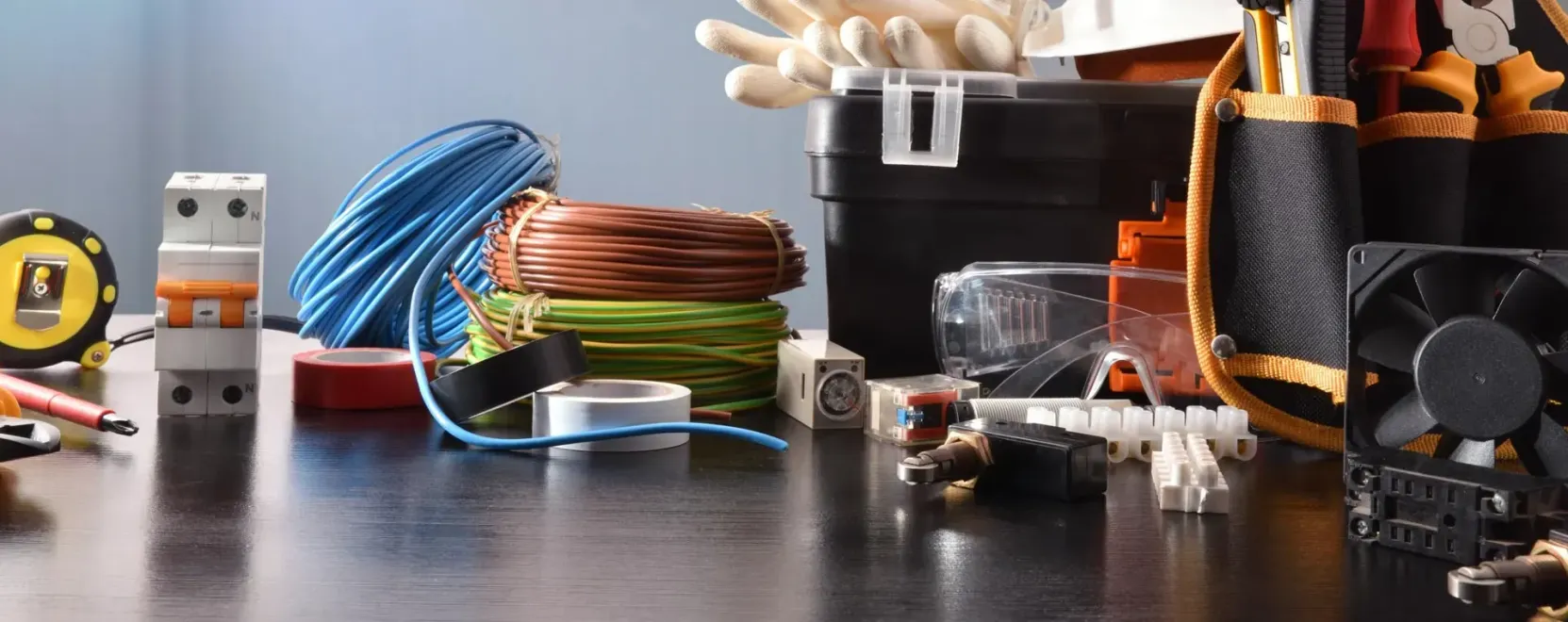 Assorted computer hardware and cables on a desk, including coiled blue and copper wires and a cooling fan.