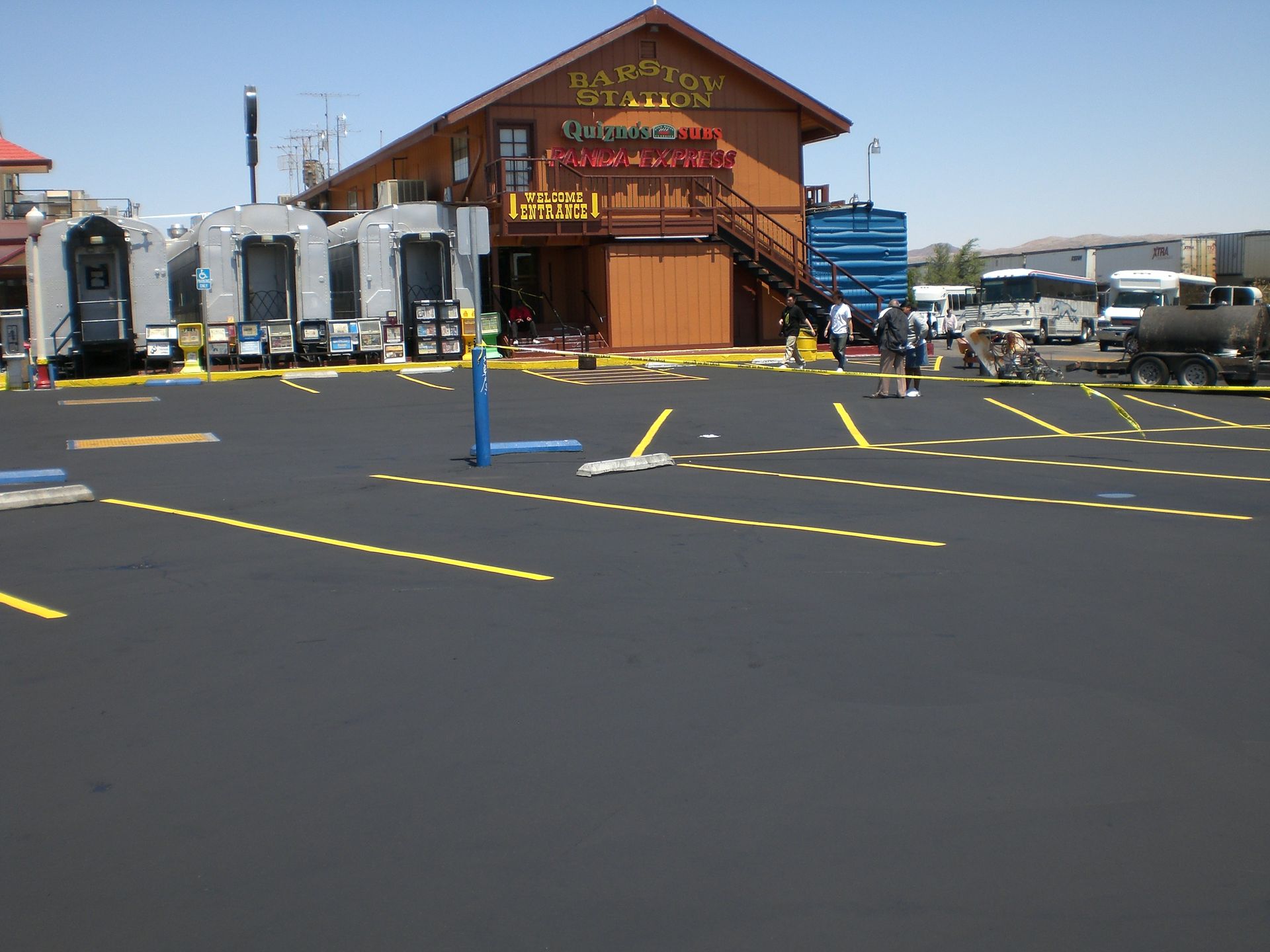Wooden lodge-style building with parking lot and blue bollards under a clear sky