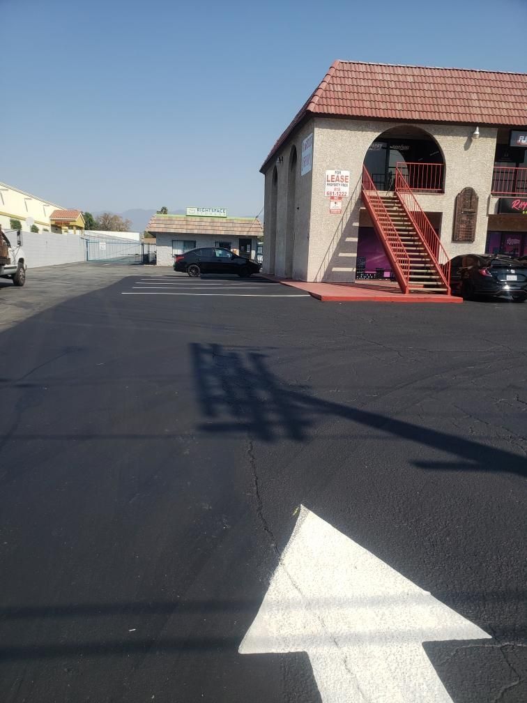 Parking lot with a large white arrow painted on asphalt beside a building with red stairs.