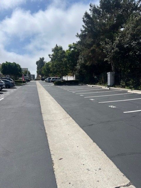 Empty parking lot with a wide light-colored center lane under a cloudy sky