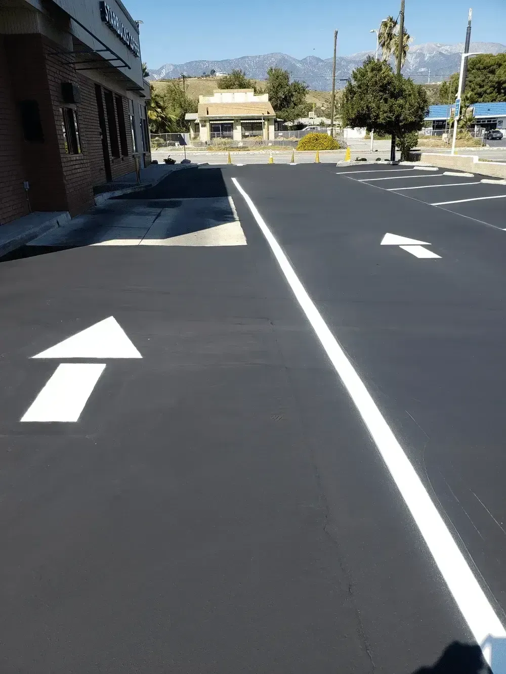 Empty parking lot with white directional arrows and mountains in the distance