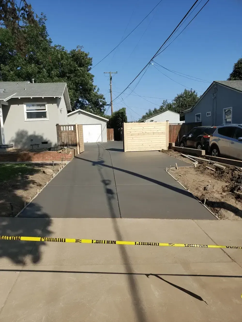 Blocked residential alley with yellow caution tape across the foreground and a white barricade at the far end.
