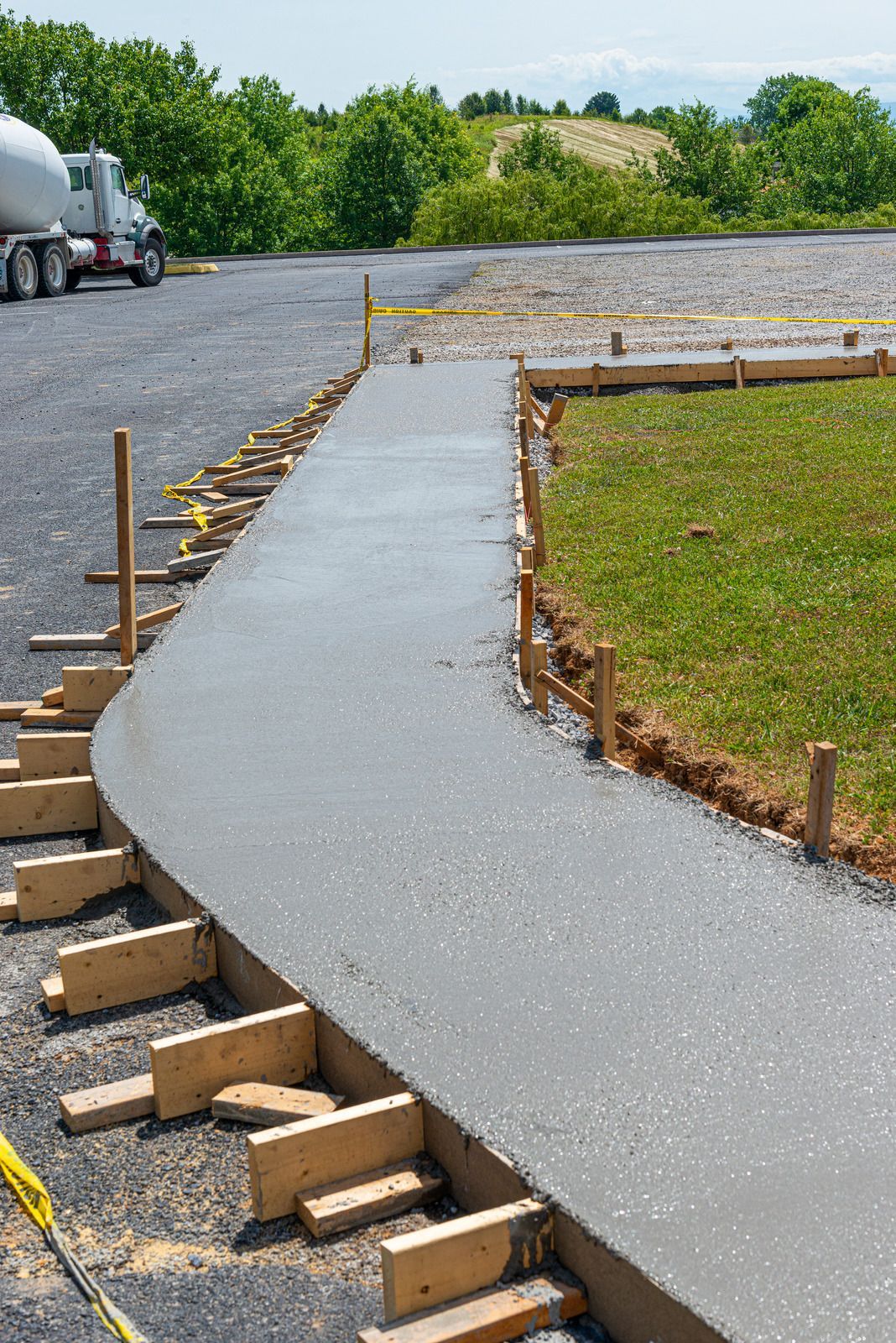 Workers spreading concrete on a rural road under construction