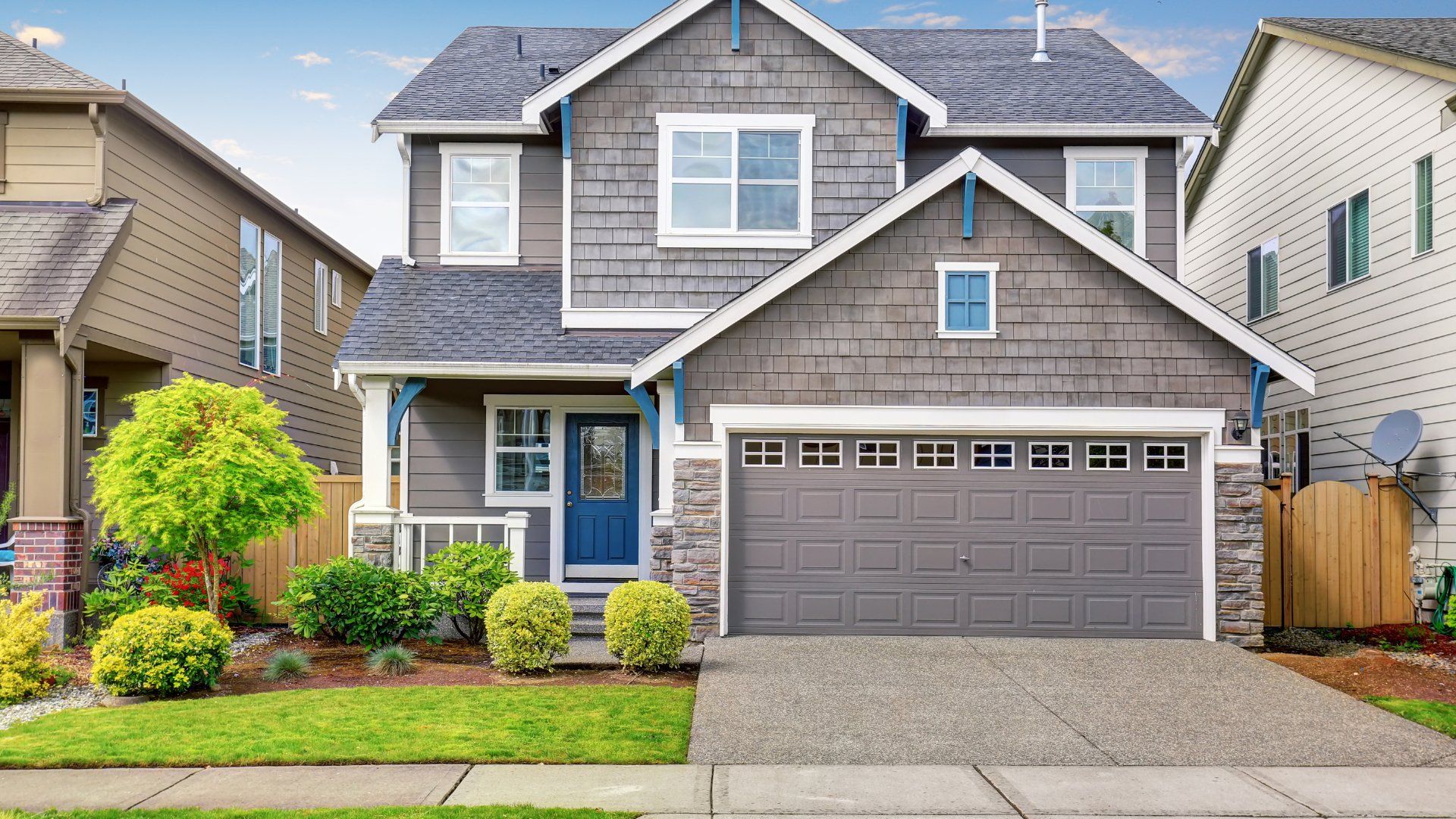 Small concrete driveway in front of a grey house with blue trim.