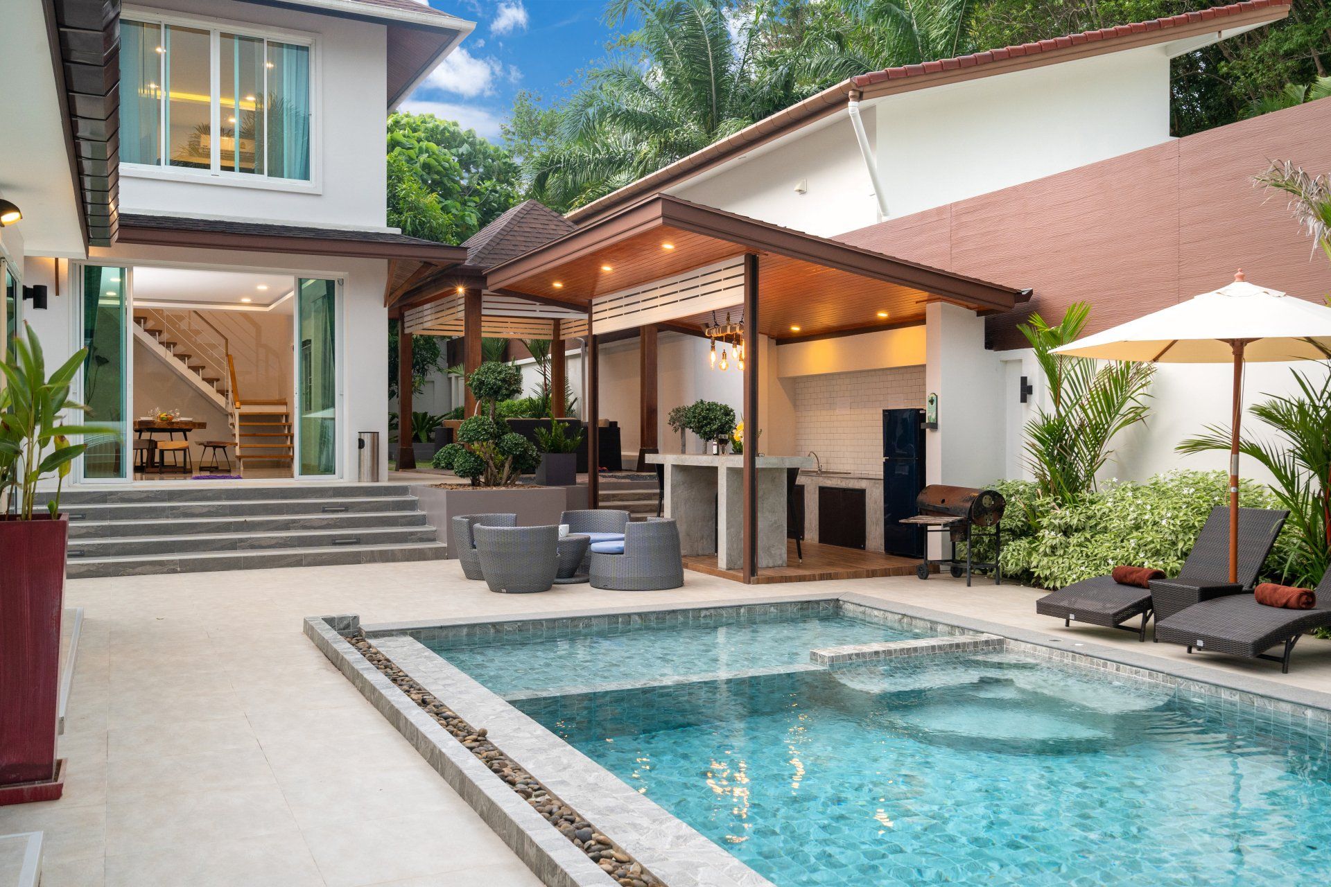 Small backyard pool with some nice landscaping, outdoor furniture and a pool bar. The pool deck is stamped concrete with concrete borders.