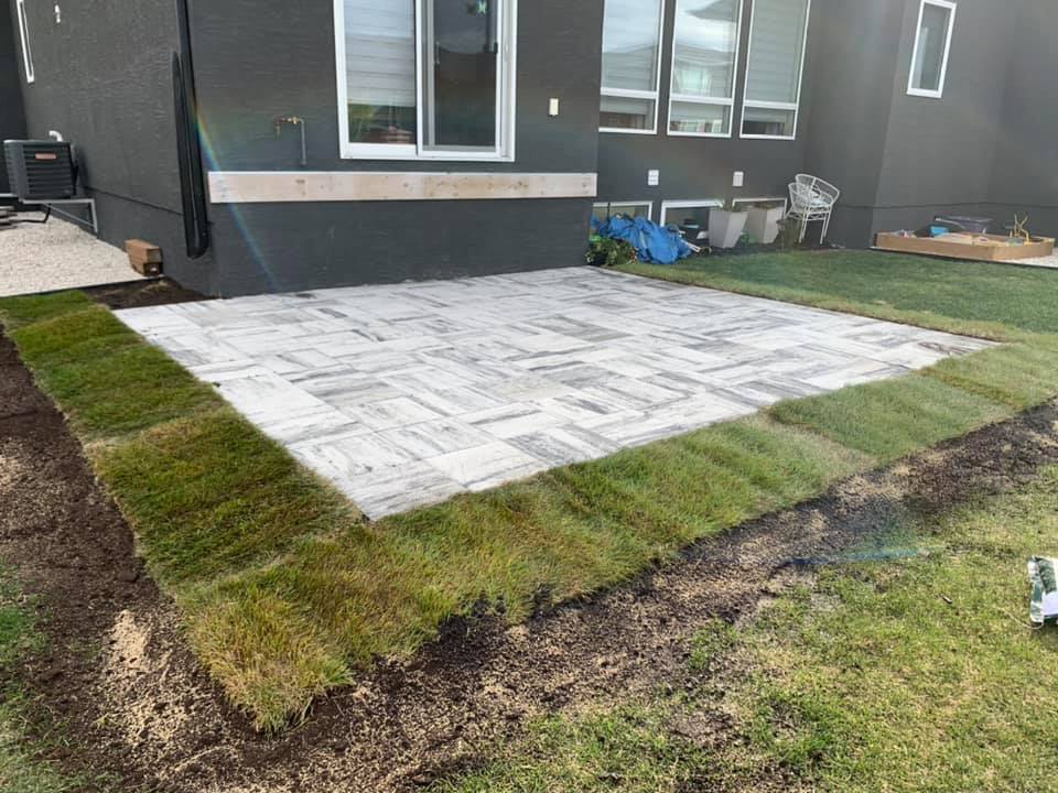 Stamped concrete patio in a backyard.  There is new turf grass around the patio.