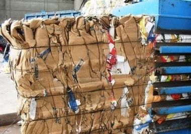 Una grande pila di cartone viene schiacciata da una macchina