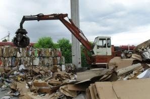 Una grande pila di cartone viene schiacciata da una macchina