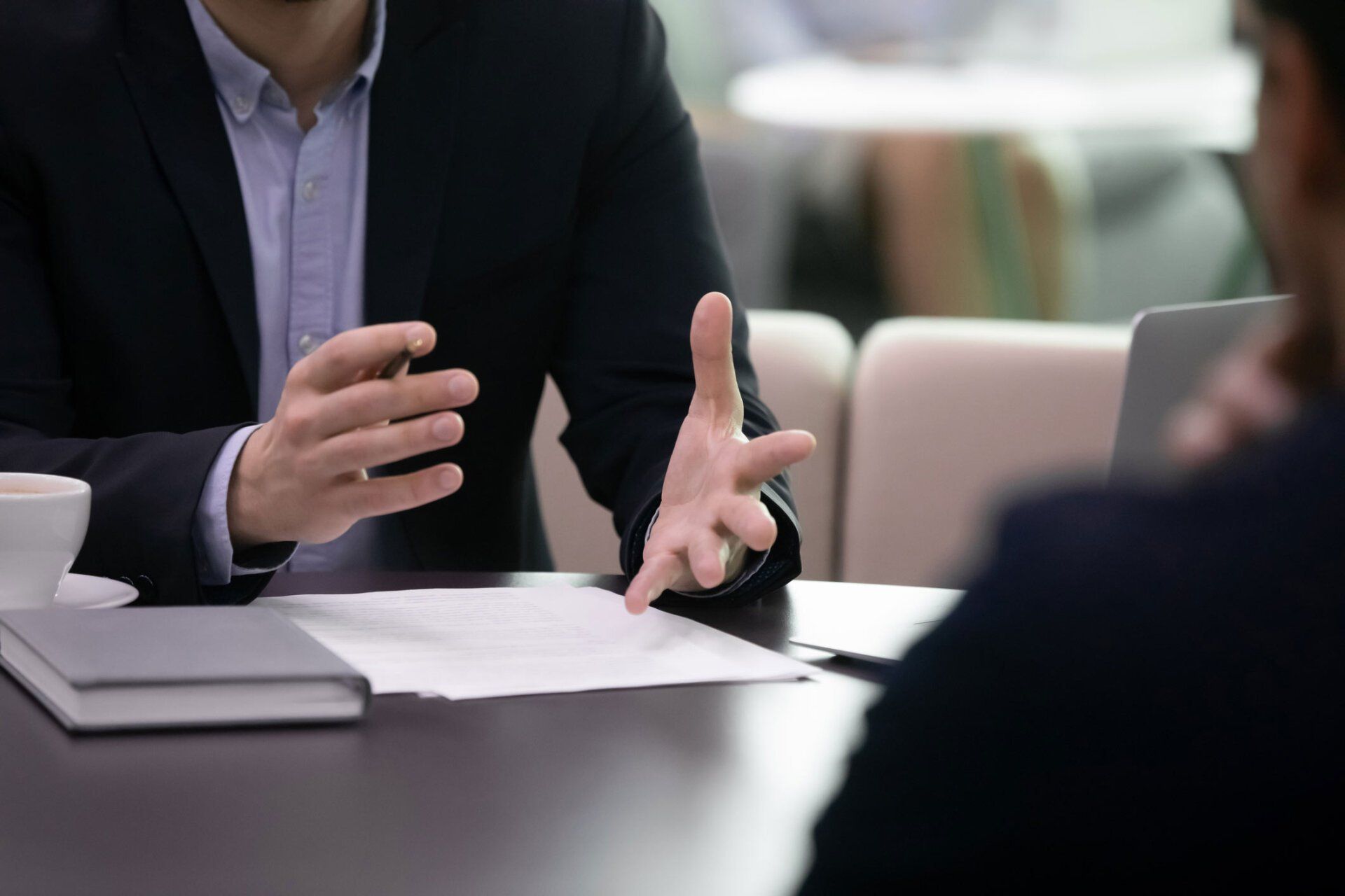 Business meeting with a person gesturing over papers at a conference table