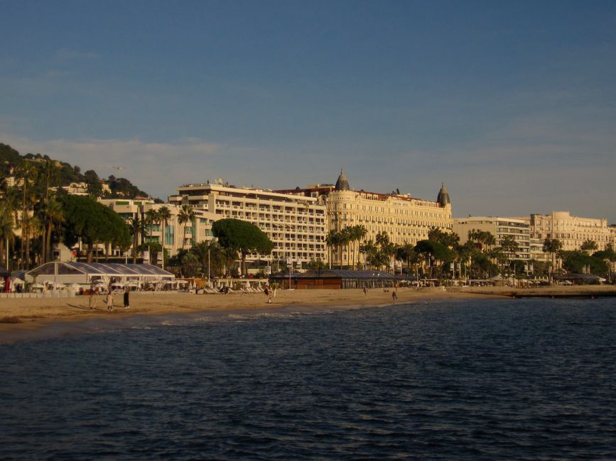 The Croisette seafront in Cannes with sandy beach and palm trees