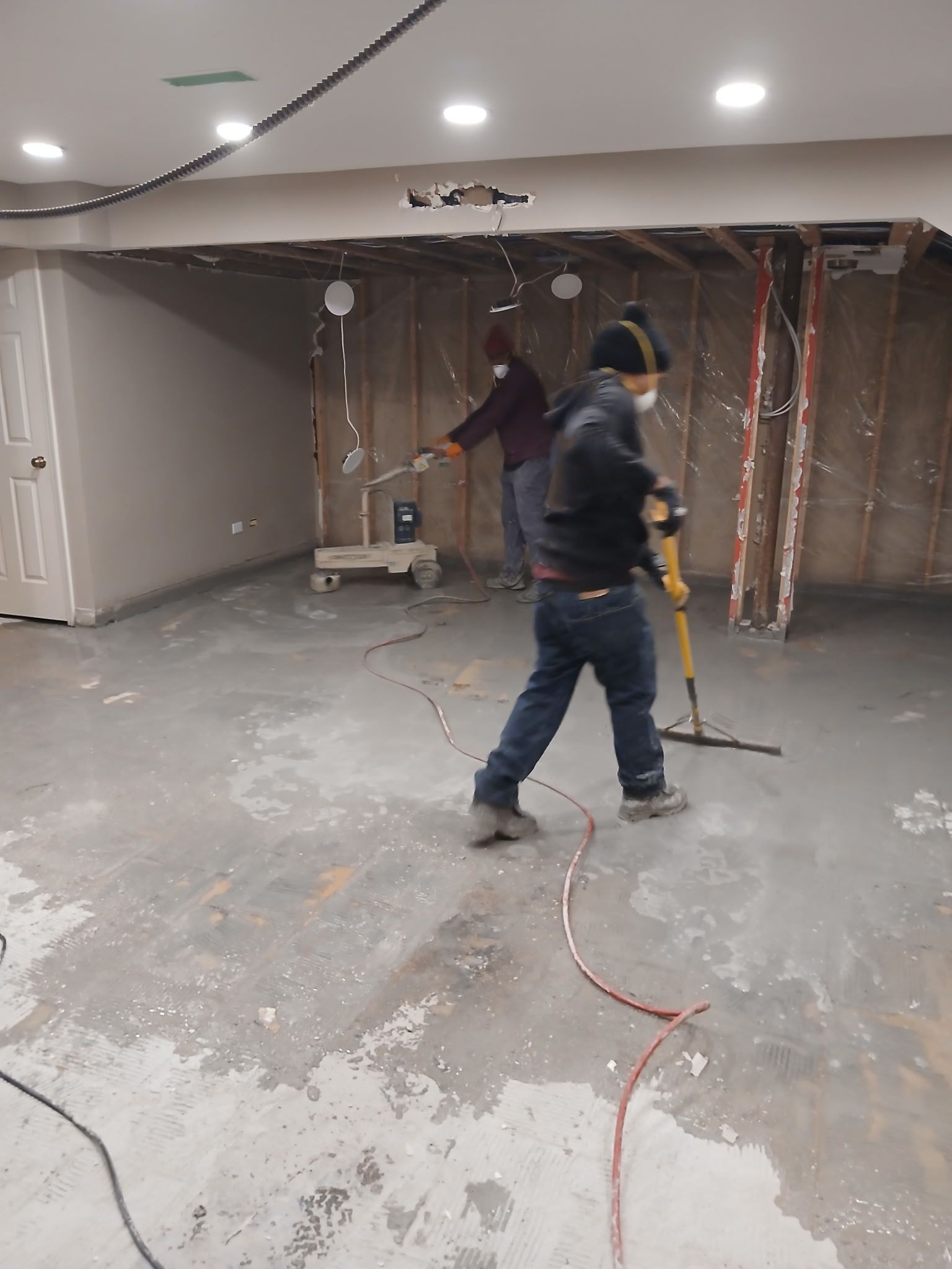People working in a gutted room with exposed wiring and drywall during renovation