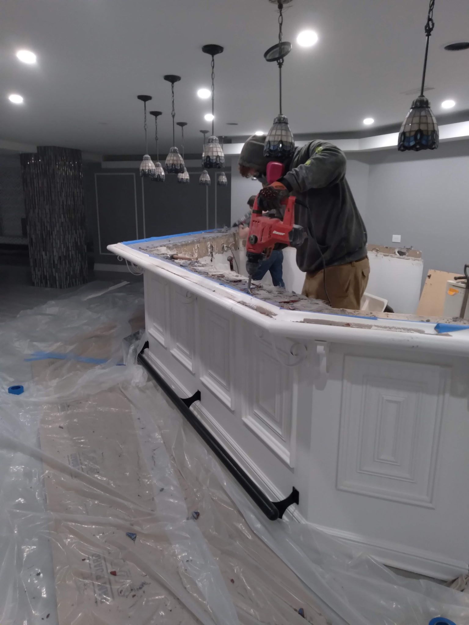 Two people work behind a white kitchen island in a partially finished modern kitchen.