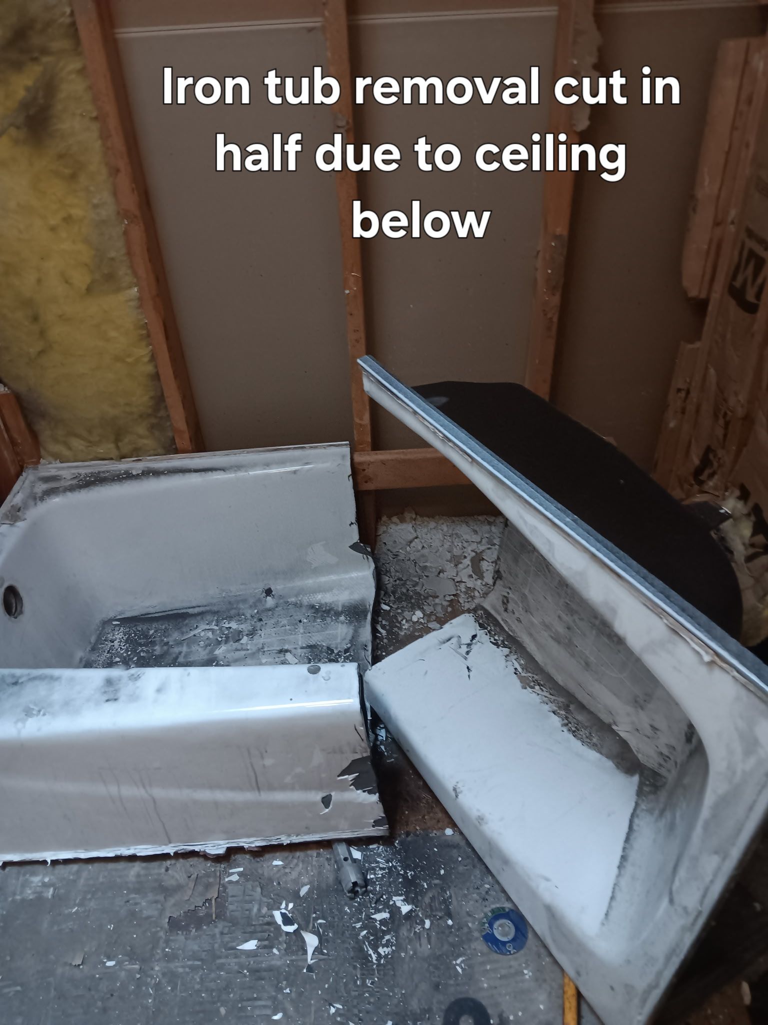 Broken white bathtub cut in half beside wall, with text noting it was cut due to low ceiling.